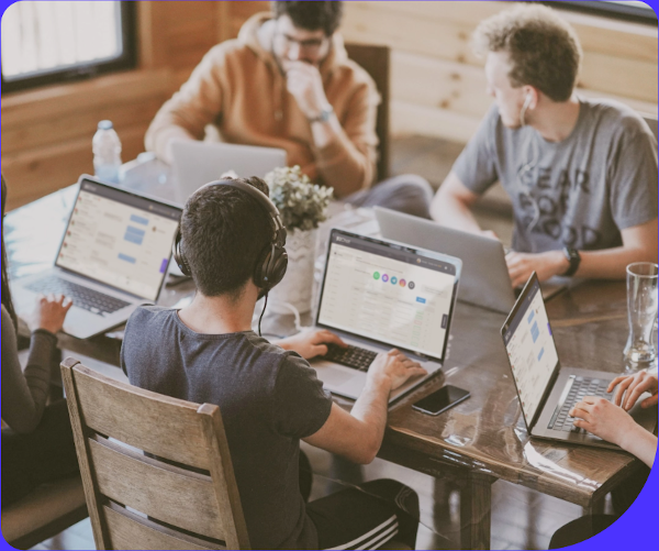 Personas en una mesa interactuando con computadores