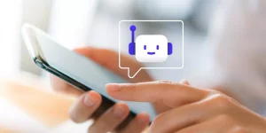 mano sosteniendo smartphone con emoji de chatbot
