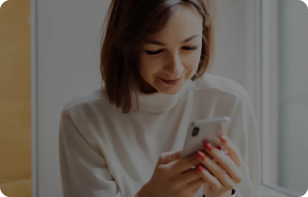 mujer sonriendo mirando su celular