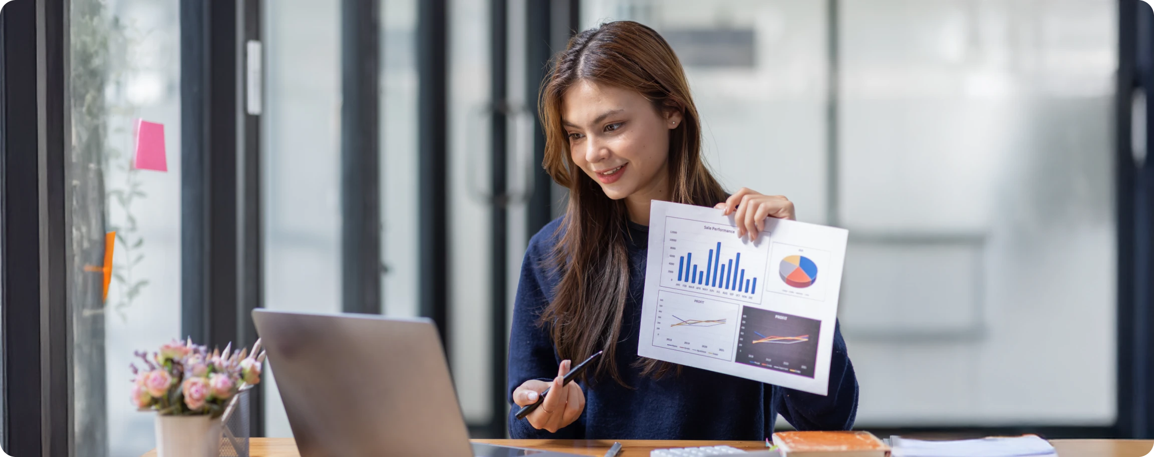 ejecutiva mostrando gráficos frente a una laptop