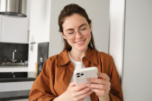 Mujer profesional usando WhatsApp Business en su smartphone para gestionar mensajes de clientes